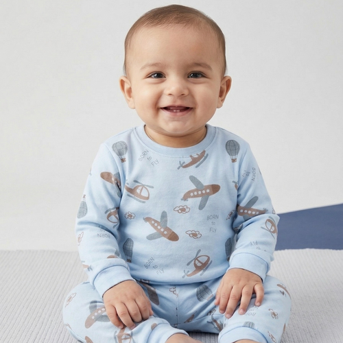 Baby wearing a blue pajama set with airplane pattern on a light gray background
