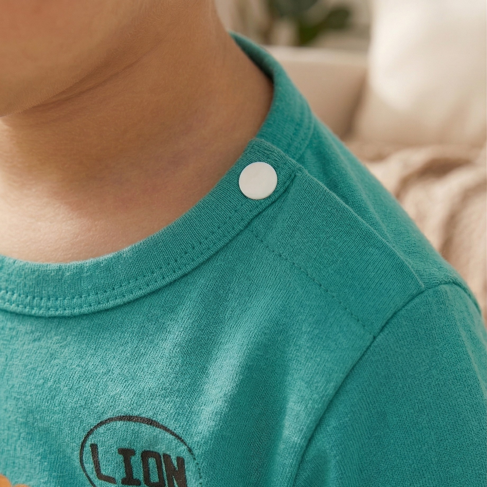 Close-up of a child wearing a teal shirt with a lion graphic and 'LION' text.