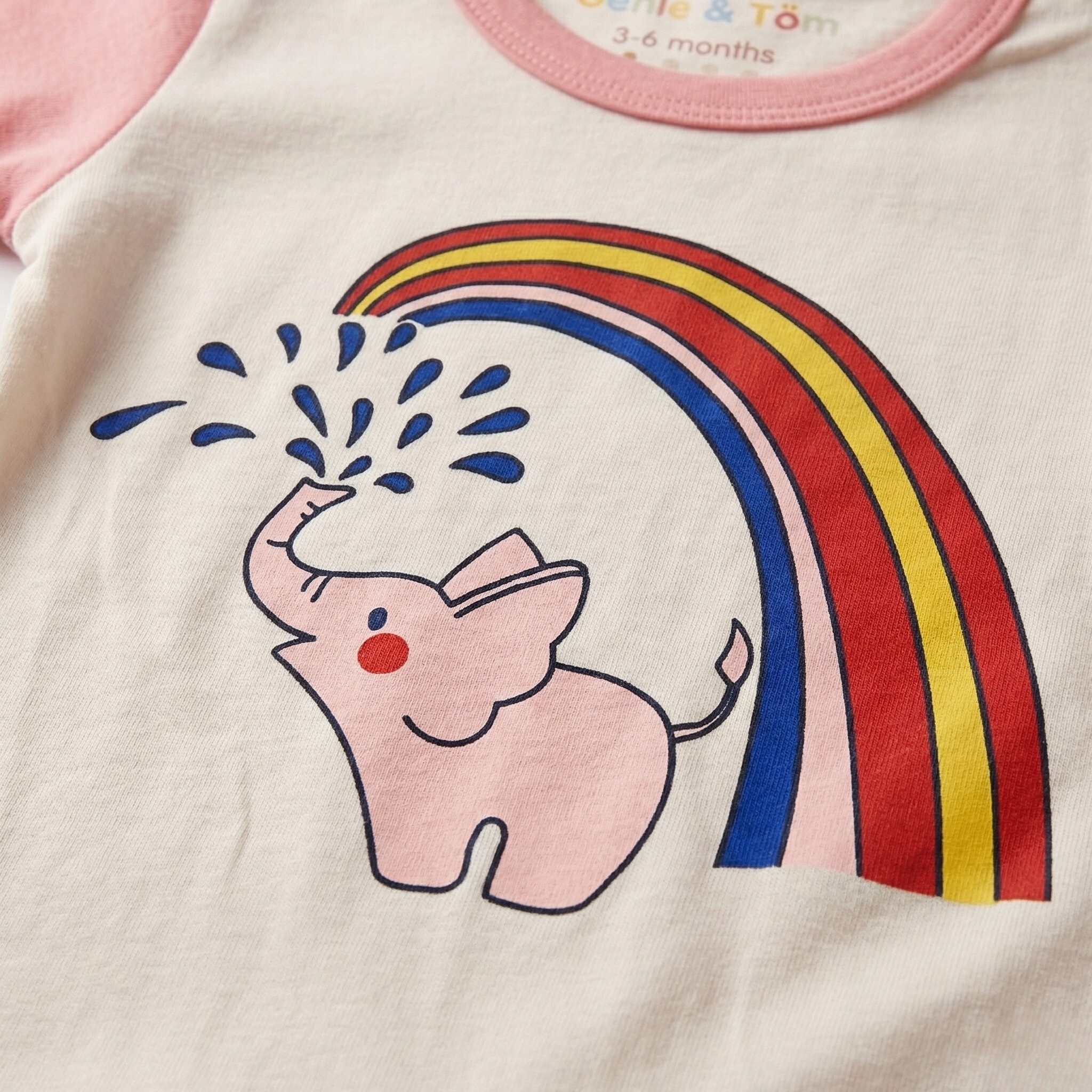 Children's clothing with a pink elephant and rainbow design on a light background