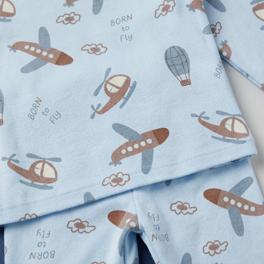 Children's pajama set with airplane and helicopter pattern on light blue fabric.